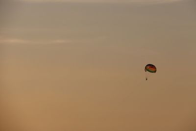 Low angle view of person paragliding against sky during sunset