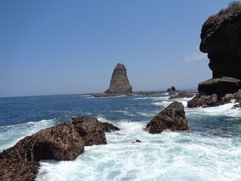 Rocks in sea against clear sky