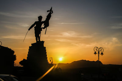 Silhouette statue against sky during sunset