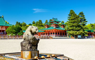 Statue by temple against sky