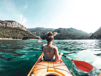 Rear view of man sitting on boat against mountain