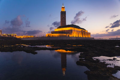 Reflection of illuminated building in sea at sunset