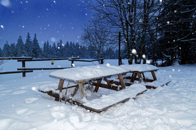 Snow covered wooden table and benches in a garden