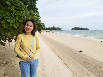 Portrait of smiling young woman standing on beach