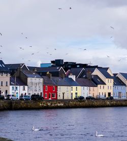 Houses by sea against sky in city