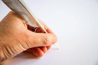 Close-up of hand holding paper over white background
