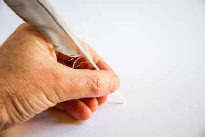 Close-up of hand holding paper over white background