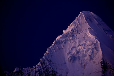 Low angle view of snow covered mountains against sky