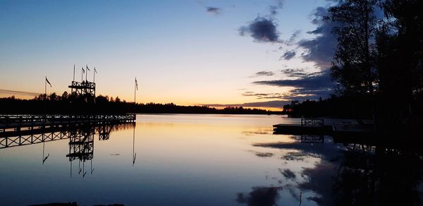 Silhouette trees by lake against sky during sunset