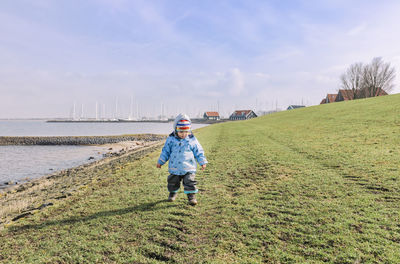 Full length of boy walking on field against sky