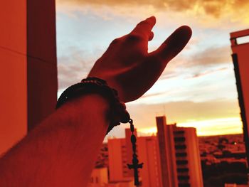 Close-up of hand against sky during sunset