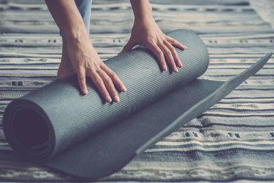 Cropped hands of woman rolling exercise mat