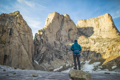 Rear view of man walking on rocks against mountains