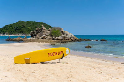 The landscape of the island rocks hill with yellow surf rescue board on the beach by summer seaside