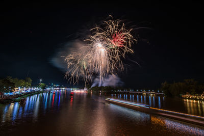 Firework display over river against sky at night