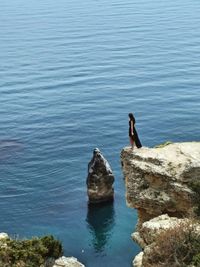 High angle view of woman standing on rock formation by sea