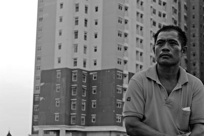 Man looking away against buildings in city