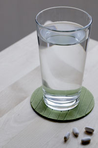 Close-up of drink of water and pills on table