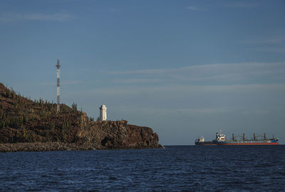 Lighthouse by sea against sky