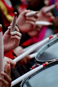 Cropped image of people playing drum with stick