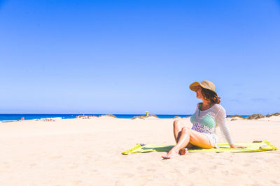 Full length of woman sitting at beach