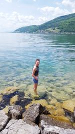 Young woman standing in lake against sky