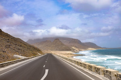 Road leading towards mountains against sky