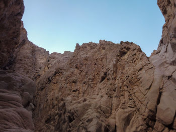 Low angle view of rocky mountains against clear sky