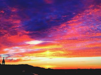 Scenic view of dramatic sky over silhouette landscape