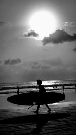 Silhouette man walking on beach against sky during sunset