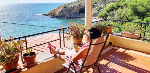 Woman sitting on chair by sea