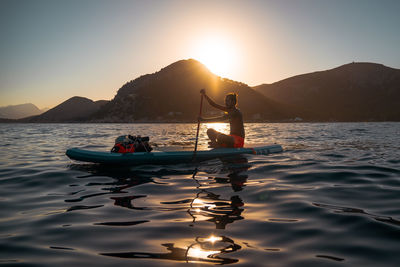 Man with paddle board over golden hour landscape