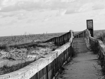 Footpath by railing against sky