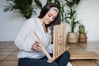 Young woman sitting on wooden floor against white wall