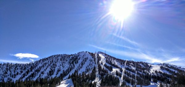 Scenic view of snowcapped mountains against blue sky on sunny day