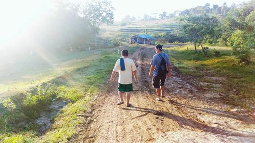 Rear view of men walking on mountain against sky