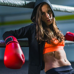 Portrait of female boxer sitting on boxing ring