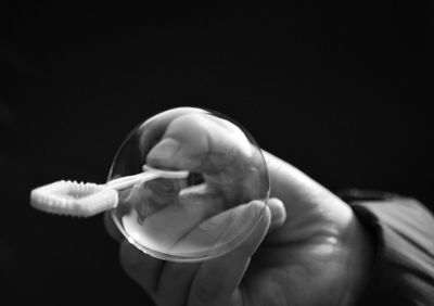 Close-up of man holding hand over black background