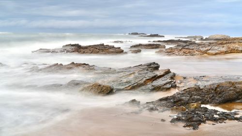 Scenic view of rocks in sea against sky