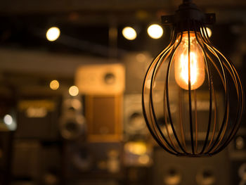 Low angle view of illuminated light bulb hanging from ceiling