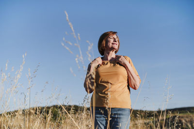 Smiling senior woman with eyes closed hiking on sunny day