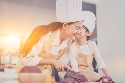 Boy kissing mother preparing food