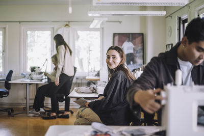 Portrait of smiling female fashion designer sitting at workshop