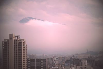 Buildings in city against cloudy sky during sunset