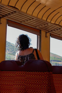 Rear view of woman sitting by window