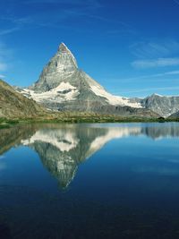 Scenic view of lake and mountains against blue sky