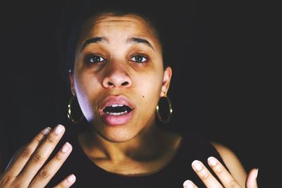 Close-up portrait of young woman against black background