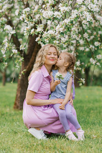 Daughter kisses mom on the cheek in the spring park