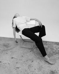 Man sitting on chair at beach against sky