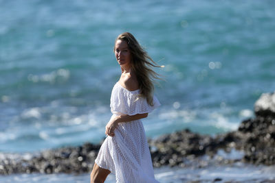 Woman with umbrella standing on beach